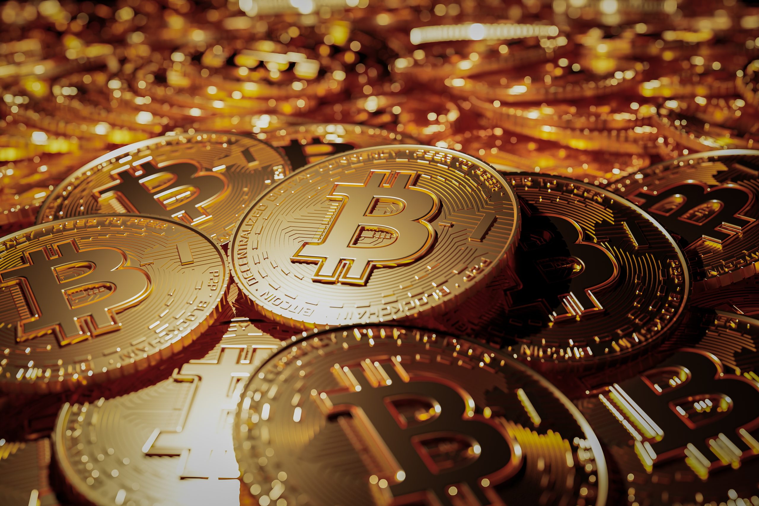 Close-up of gold Bitcoin coins with the BTC logo, reflecting warm light.