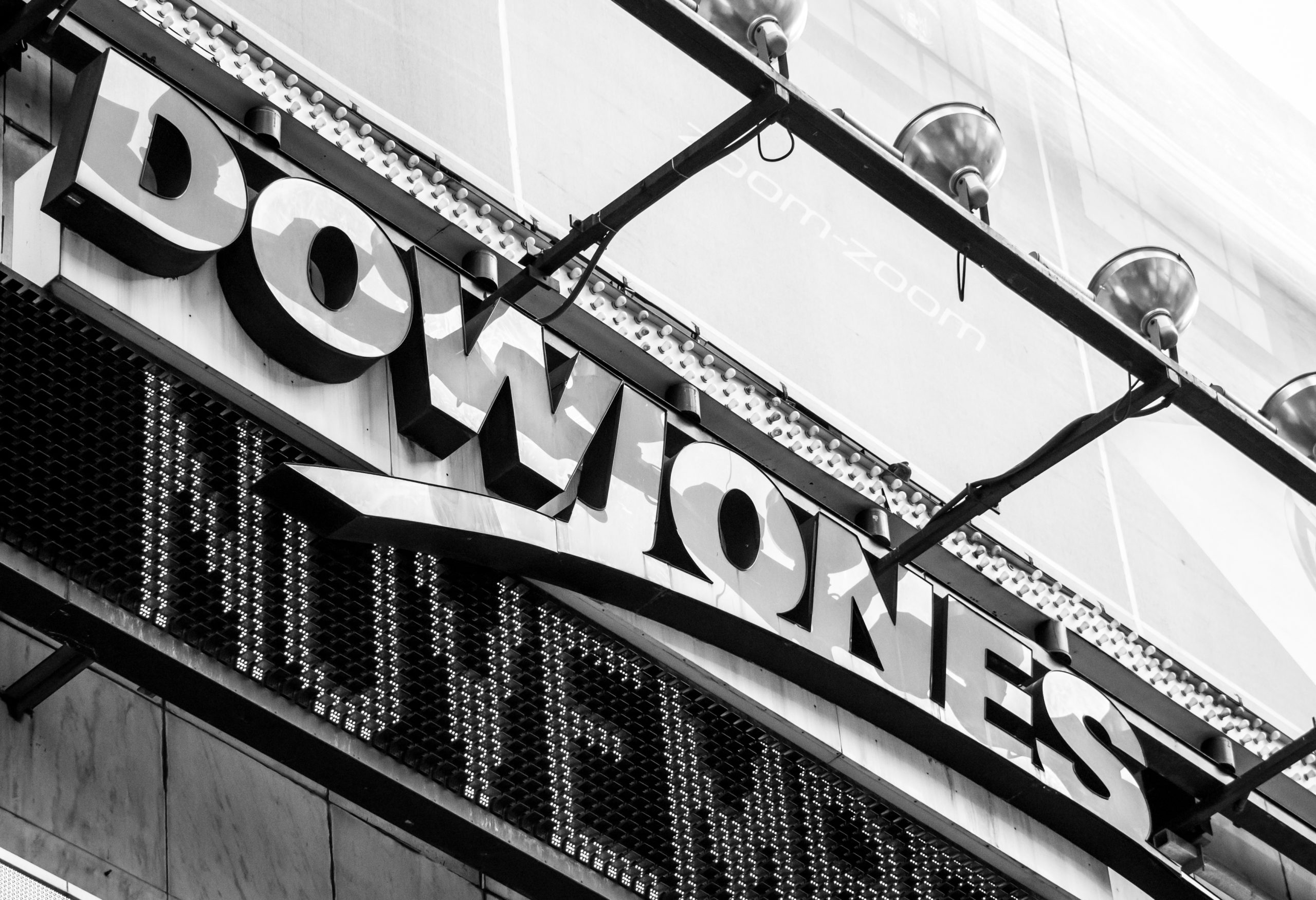 Close-up of a diagonal storefront marquee with illuminated bulb lights along the edges and bold letters partially visible in black and white photography.
