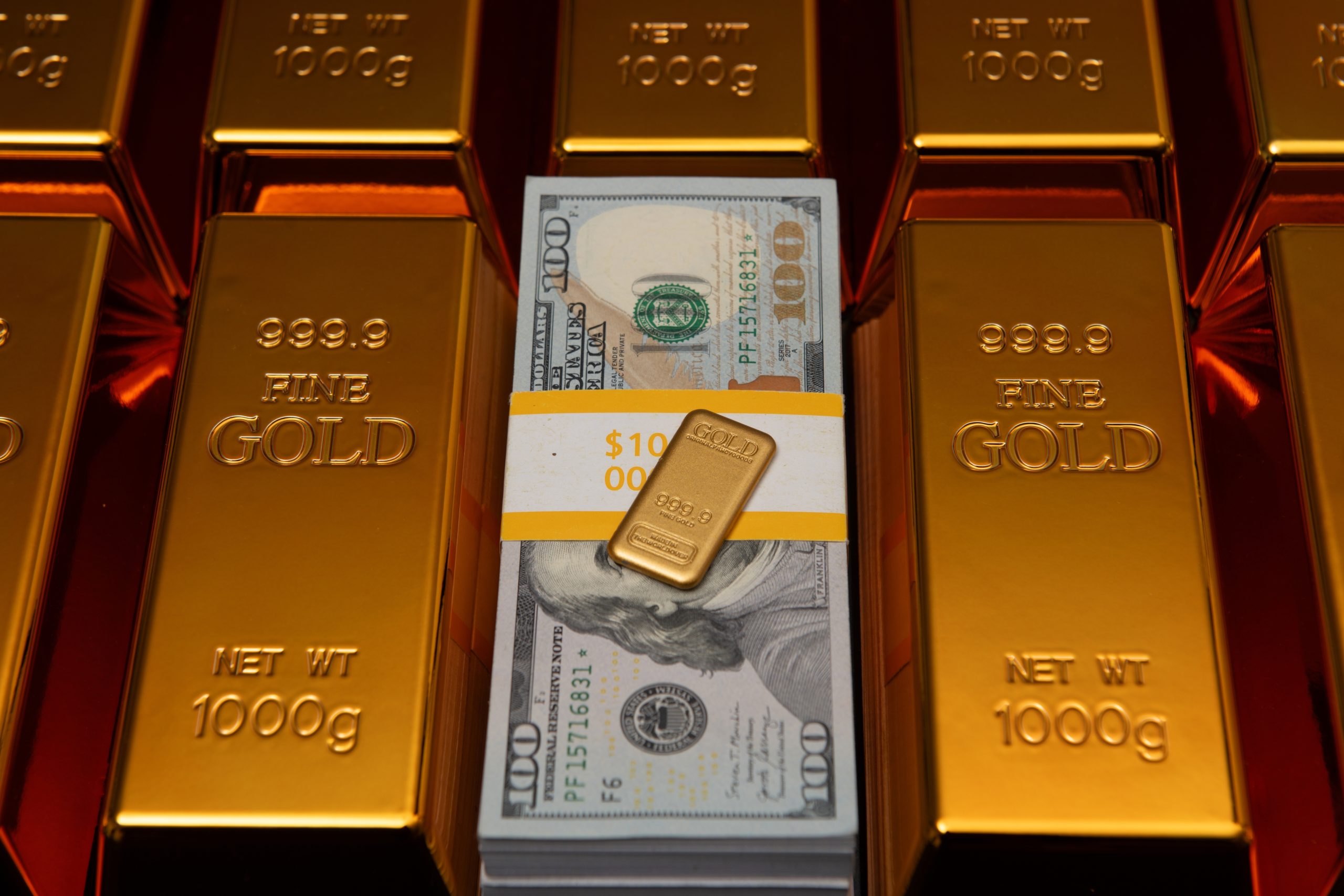 Stack of gold bars with a bundle of US $100 bills in the center, conveying wealth